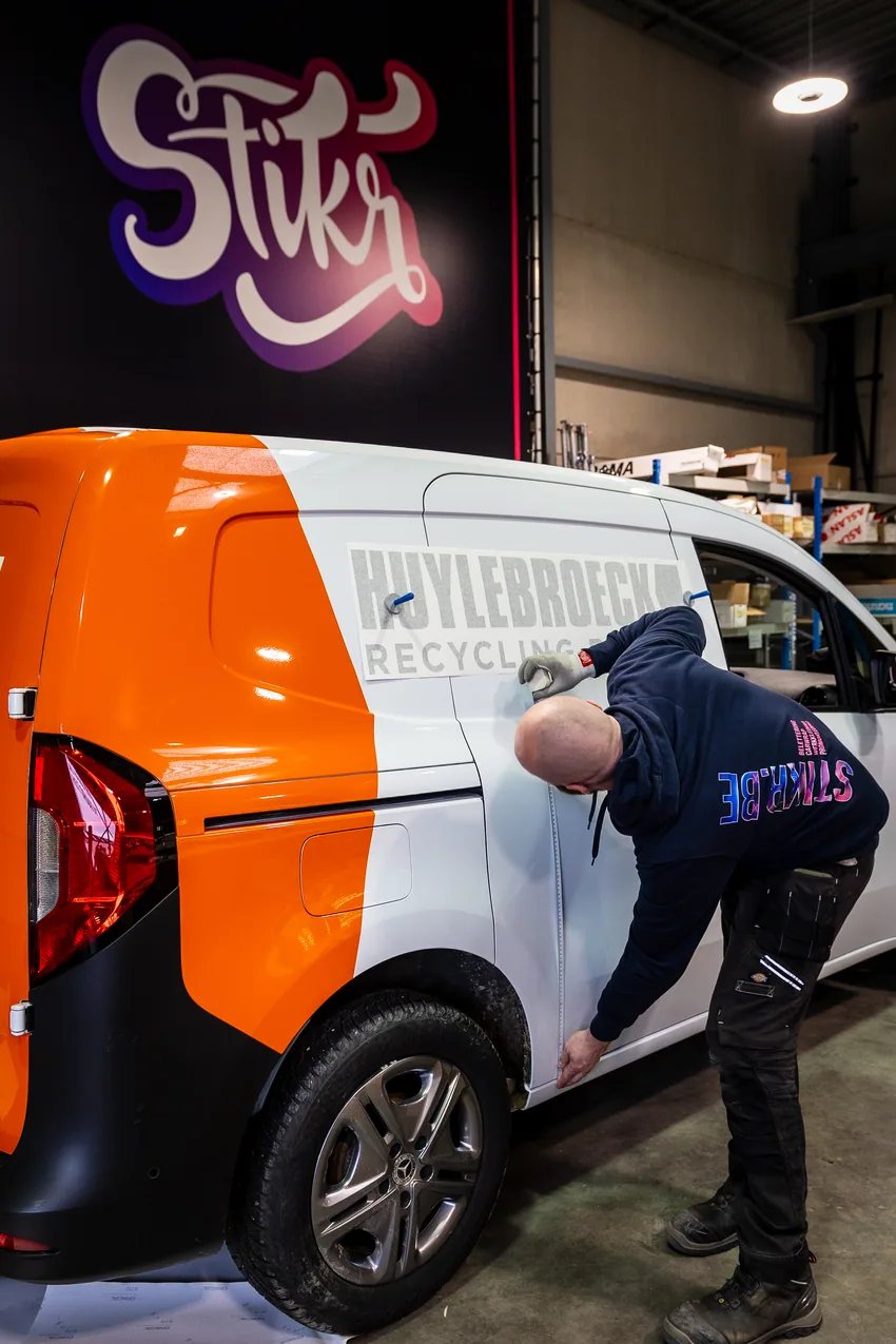 Stikr medewerker monteert belettering op een bestelwagen